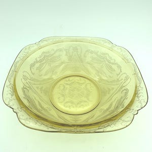 Puede incluir: Una fuente de vidrio te&ntilde;ido de amarillo con forma ovalada y un dise&ntilde;o decorativo grabado. La fuente tiene un borde festoneado y un cuenco central, m&aacute;s peque&ntilde;o y circular. El patr&oacute;n grabado incluye motivos florales y de volutas.