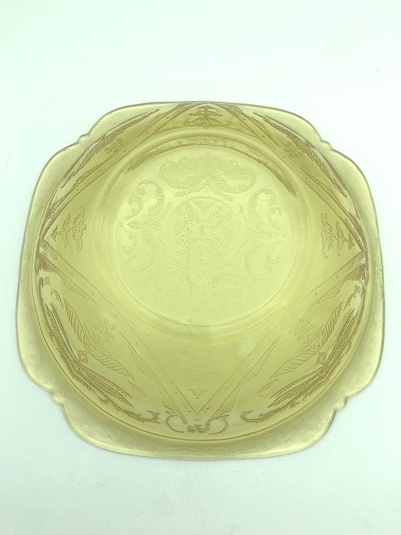 Puede incluir: Un cuenco de vidrio amarillo vintage con forma cuadrada y bordes festoneados. El cuenco presenta un dise&ntilde;o floral y geom&eacute;trico grabado. El cuenco es probablemente de la &eacute;poca de la Depresi&oacute;n y es una pieza decorativa.