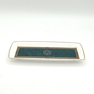 May include: Rectangular serving tray with a white border and a teal and gold decorative center. The center features a textured teal background with a gold and black geometric design. The tray has gold trim.