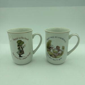 Set Of 2 Vintage 1979 WWA Inc. Holly Hobbie 10 Ounce Porcelain Coffee Mugs Cups Includes &quot;Happy Is The Heart&quot; & &quot;Happy Times Are Remembered&quot;
