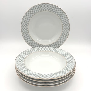 May include: Set of white ceramic soup bowls with a gray checkered pattern around the rim and a gold-colored trim. The bowls are stacked in a neat pile, with one bowl placed on top.
