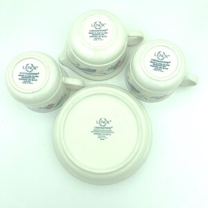 Puede incluir: Cuatro piezas de Chinastone color blanco roto de la colecci&oacute;n Lenox Poppies on Blue, incluyendo dos tazas, una jarra de leche y un platillo, mostradas boca abajo para exhibir el logo, el nombre del patr&oacute;n y el texto de apto para microondas.