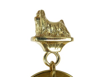 May include: Gold-coloured metal keychain featuring a detailed Yorkshire Terrier figurine. The keychain has a round ring for attaching keys.