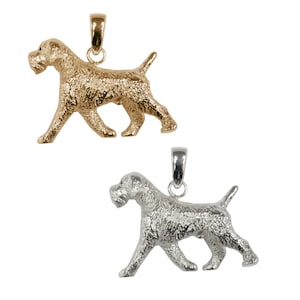 May include: Two silver pendants in the shape of a Wirehaired Pointing Griffon dog. The dog is walking with its head held high. The pendants are both silver, but one is a more polished silver and the other is a more matte silver.