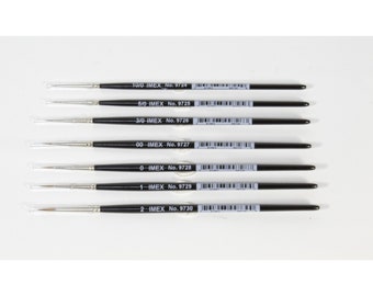 May include: A set of 7 black handled paint brushes with silver metal ferrules and white bristles. The brushes are labeled with their size and IMEX number. The sizes are 10/0, 5/0, 3/0, 00, 0, 1, and 2.