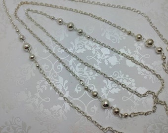 May include: A silver chain necklace with three strands and round beads.