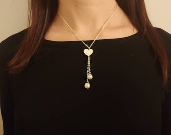 May include: A silver necklace with a heart pendant and two pearl drops.