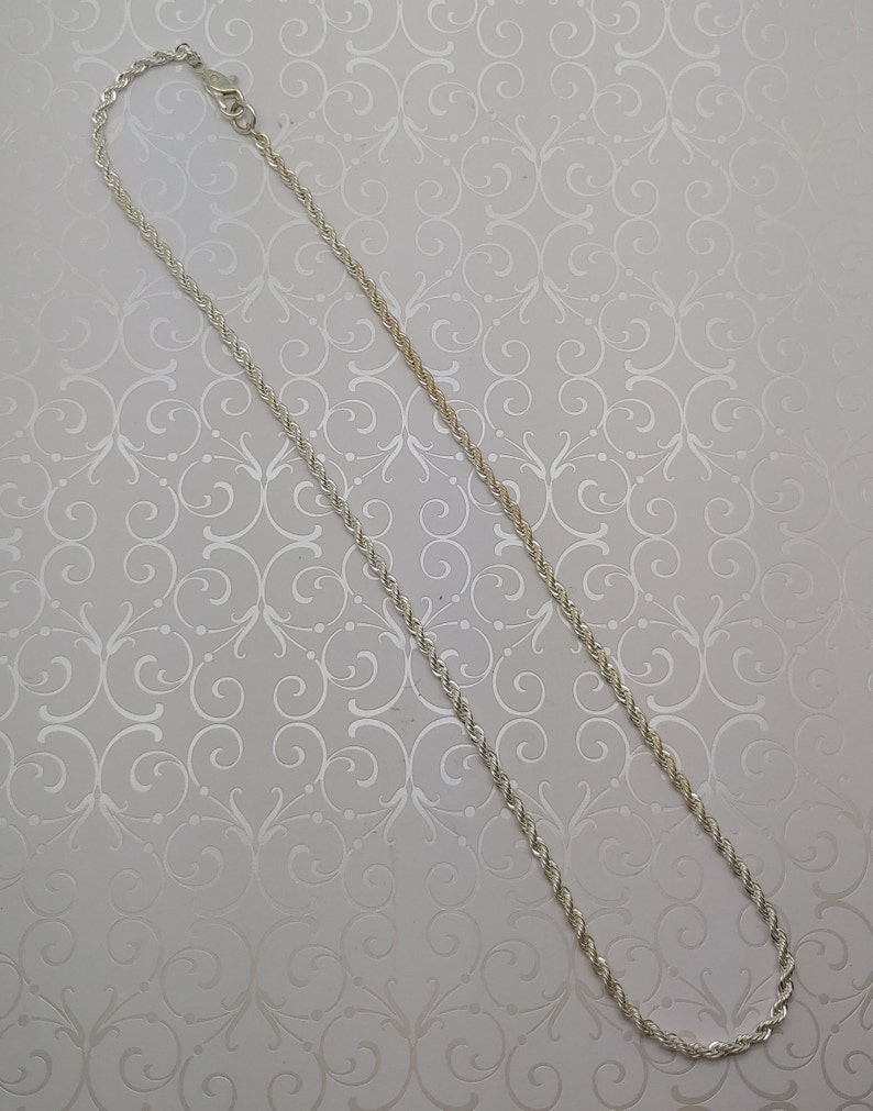 May include: A silver rope chain necklace with a lobster clasp.