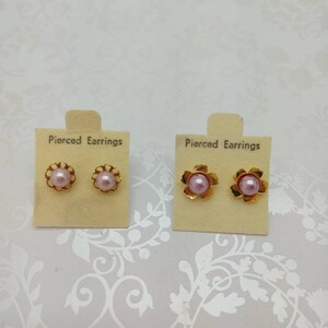 May include: Two pairs of gold pierced earrings with pink pearl centres. The earrings are displayed on small cards with the text "Pierced Earrings".