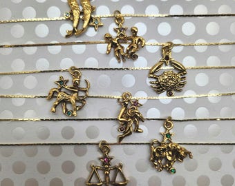 May include: A set of 12 gold zodiac sign charms with colourful gemstones. Each charm is on a delicate gold chain.