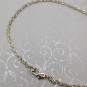 May include: A silver rope chain necklace with a lobster clasp closure.