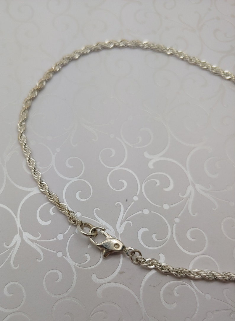 May include: A silver rope chain necklace with a lobster clasp closure.
