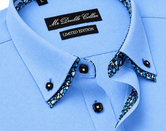 Könnte beinhalten: Ein hellblaues Hemd mit Knopfleiste und doppeltem Kragen, der innen sowie an der Knopfleiste mit einem schwarz-blau-weißen Blumenmuster versehen ist. Das Hemd hat schwarze, quadratische Knöpfe mit weißer Naht und ein Etikett mit der Aufschrift Mr Double Collar.