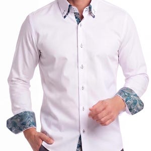 Peut inclure: Une chemise blanche à manches longues avec un motif cachemire bleu sarcelle et gris contrastant sur l'intérieur du col, les poignets intérieurs et la patte de boutonnage intérieure. La chemise possède un col boutonné et une fermeture centrale.