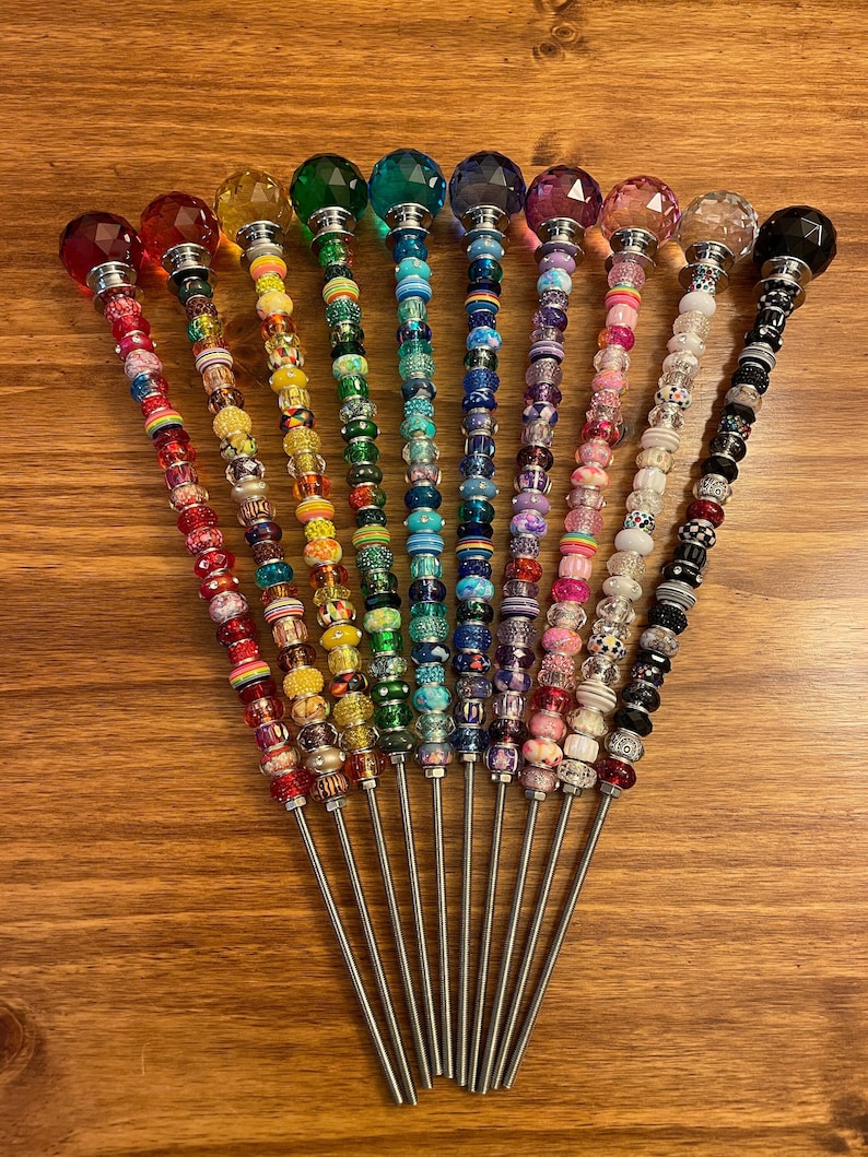 May include: Ten colorful beaded wands with crystal tops. Each wand has a different color scheme and features a variety of beads, including clear, opaque, and patterned beads.