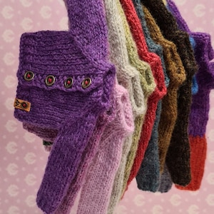 May include: A collection of knitted sweaters in various colors, including purple, pink, gray, green, red, blue, brown, and black. The sweaters have a ribbed texture and are hanging on a rack.