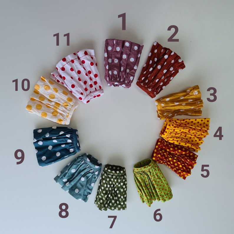 May include: Ten different fabric skirts with polka dots in various colors, including red, yellow, blue, green, and brown. The skirts are arranged in a circle, numbered 1 through 10.