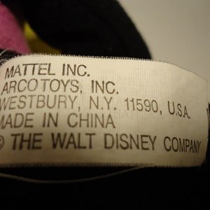 May include: A white tag with black text that reads "MATTEL INC. ARCO TOYS, INC. WESTBURY, N.Y. 11590, U.S.A. MADE IN CHINA &copy; THE WALT DISNEY COMPANY"
