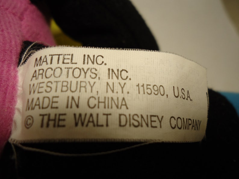 May include: A white tag with black text that reads "MATTEL INC. ARCO TOYS, INC. WESTBURY, N.Y. 11590, U.S.A. MADE IN CHINA &copy; THE WALT DISNEY COMPANY"