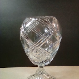 May include: A clear glass vase with a geometric pattern and a square base.