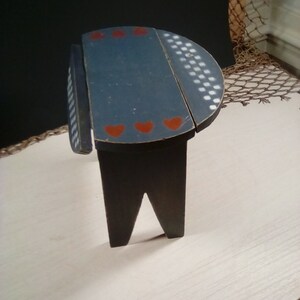 May include: A small, wooden stool with a blue painted top and red hearts. The top is divided into two sections, one with white checkered pattern and the other with red hearts.