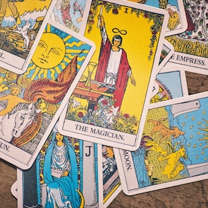 May include: A spread of tarot cards featuring the Fool, the Sun, the Magician, the Empress, and the Moon. The cards are colorful and feature illustrations of various figures and symbols.