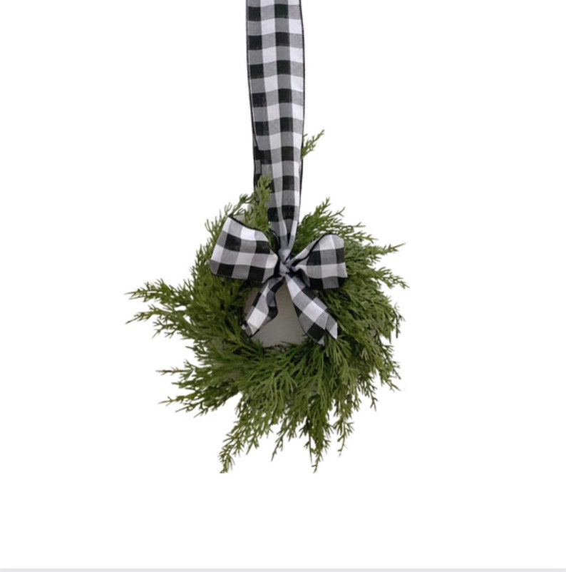 Op de afbeelding: Een kleine groene krans met een zwart-wit geblokte strik.