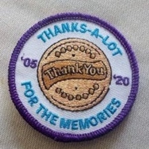 May include: A round, white patch with a purple border. The patch has a brown cookie with the text "Thank You" on it. The text "Thanks-A-Lot for the Memories" is written around the cookie. The years "'05" and "'20" are on either side of the cookie.