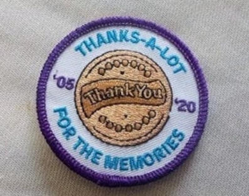 May include: A round, white patch with a purple border. The patch has a brown cookie with the text "Thank You" on it. The text "Thanks-A-Lot for the Memories" is written around the cookie. The years "'05" and "'20" are on either side of the cookie.