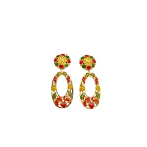 May include: A pair of gold-toned earrings with floral designs. Each earring features a round top with red, yellow, and green accents, and an oval-shaped drop with similar floral patterns. The earrings are set against a white background.