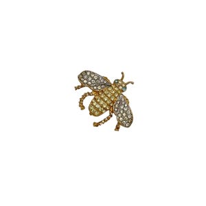 May include: A gold bee brooch with clear and yellow rhinestones. The bee has a detailed design and is a great addition to any jewellery collection.