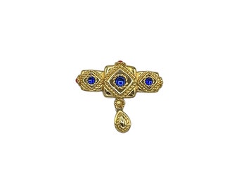 May include: A gold-toned brooch with three blue gemstones and a dangling teardrop-shaped pendant.