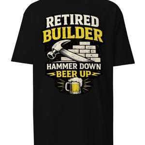 May include: Black t-shirt with a graphic design. The design features the words "Retired Builder" in white and yellow, a hammer, a brick wall, and the phrase "Hammer Down Beer Up" with a beer mug illustration.