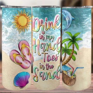 May include: A colorful tumbler with a beach scene and the text "Drink in my hand toes in the sand". The scene includes a seashell, flip flops, a palm tree, a dolphin, and a sun.