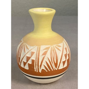 Peut inclure: Petit vase en céramique peint à la main, corps arrondi et col étroit. Le haut est jaune, dégradé en une bande orange clair avec des motifs blancs sculptés. La base est blanche avec des rayures noires et marron.
