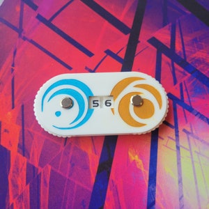 May include: White plastic counter with a blue and gold design. The counter has two round dials with a number "56" displayed.