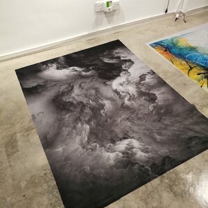 May include: A black and white photographic print of a cloudy sky. The print is on a flat surface and has a textured look.