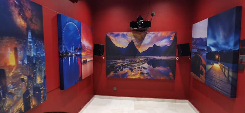 May include: Four framed canvas prints with different scenic images. The prints are hung on a red wall. The images include a city skyline, a Ferris wheel, a mountain range, and a body of water.