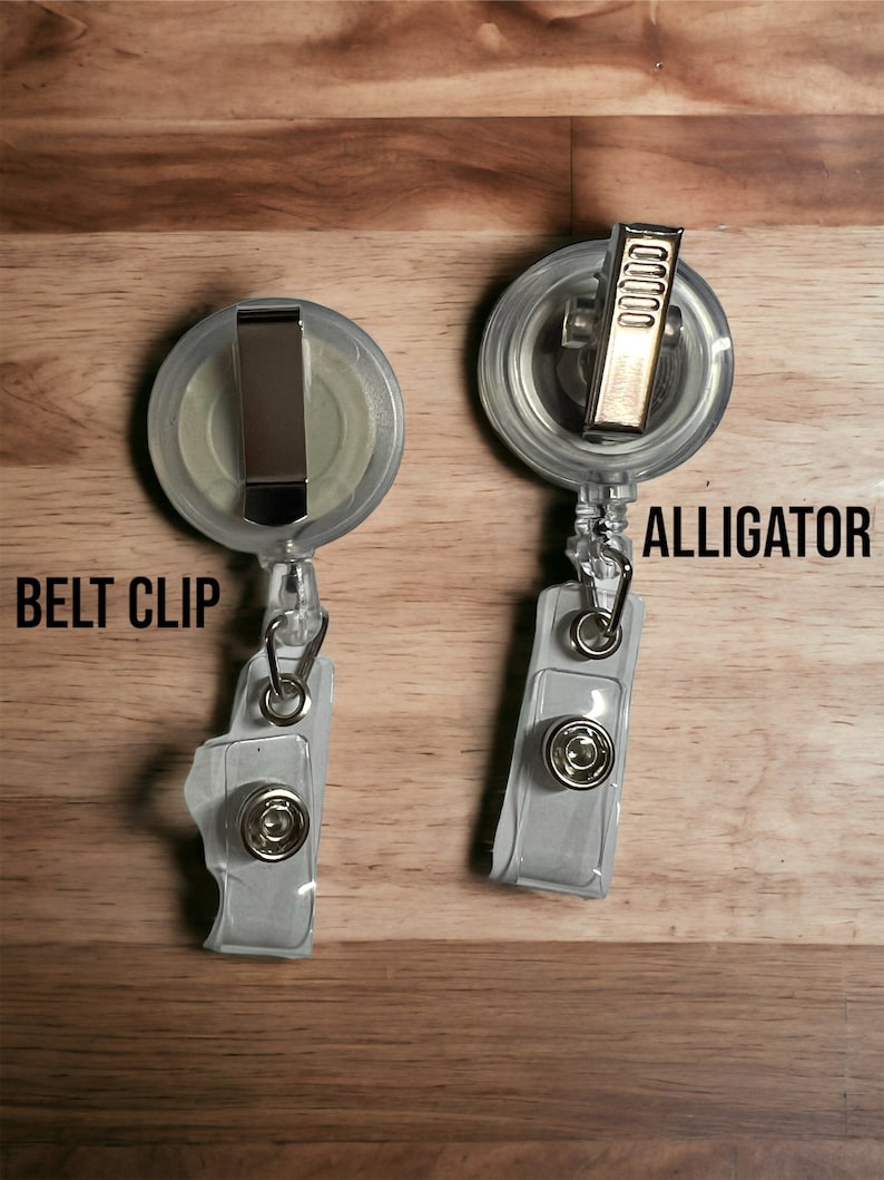 May include: Two clear plastic retractable badge holders with a silver belt clip and a gold alligator clip. The text "BELT CLIP" is printed on the left holder and "ALLIGATOR" is printed on the right holder.