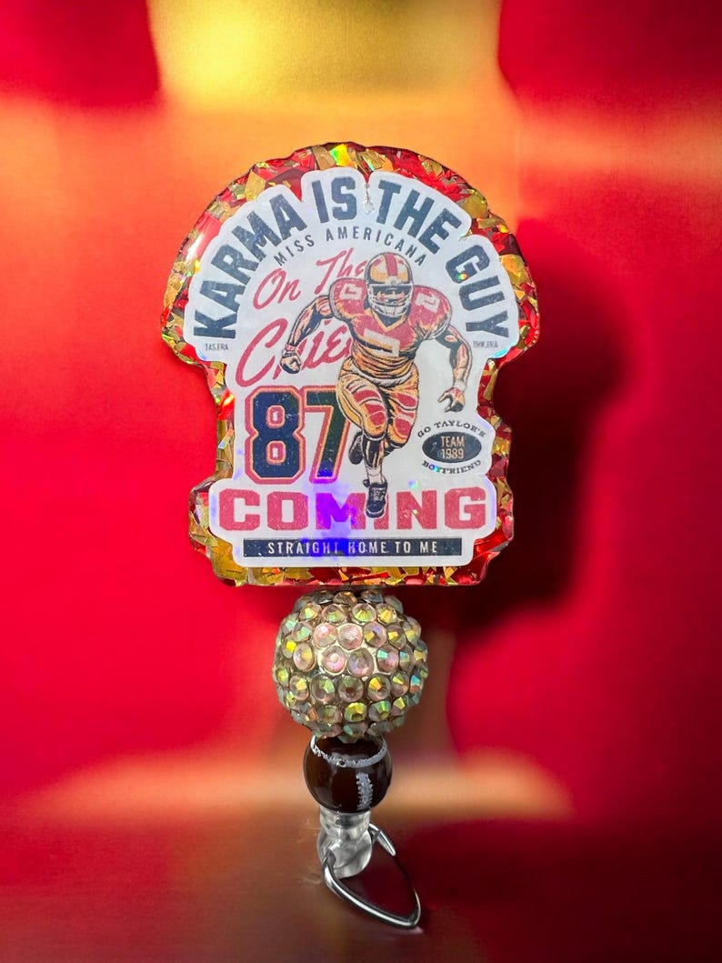 May include: A red, white and gold resin keychain with a football player graphic and the text "Karma is the guy, Miss Americana, On the Chiefs, 87, Go Taylor's Team 1989 Boyfriend, Coming, Straight Home to Me".