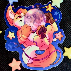 Op de afbeelding: Een sticker met een cartoonvos die een ruimtepak draagt en een transparante bel vasthoudt. De vos wordt omringd door sterren op een blauwe achtergrond.