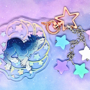 May include: A clear acrylic charm featuring a blue wolf with a starry sky design. The charm is attached to a silver chain with a rose gold star charm and several colorful star beads.