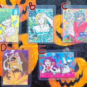 May include: Five rectangular trading cards labeled A through E, each featuring colorful, stylized character illustrations. The cards display various figures in vibrant settings, including a yellow-clad character, a blue-toned figure, a red-suited person, a smoking figure, and a purple-haired character holding a phone.