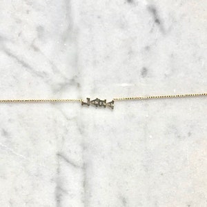 Puede incluir: Un collar de cadena de oro con la palabra "LOVE" escrita en letras peque&ntilde;as.