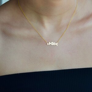 Puede incluir: Un collar de oro con una cadena delicada y un peque&ntilde;o colgante que dice "LOVE" en cursiva.