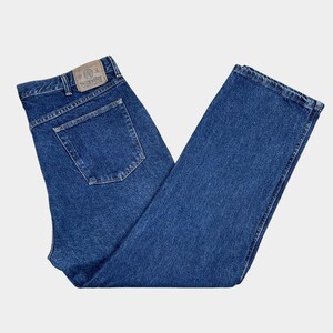 Pu&ograve; includere: Un paio di jeans blu denim con un'etichetta Wrangler in pelle marrone sulla tasca posteriore.