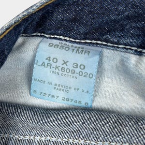 Pu&ograve; includere: Un'etichetta in denim blu con testo bianco che recita "96501MR", "40 X 30", "LAR-K609-020", "100% COTONE", "PRODOTTO IN MESSICO CON TESSUTO U.S.", "672787 29745 0".