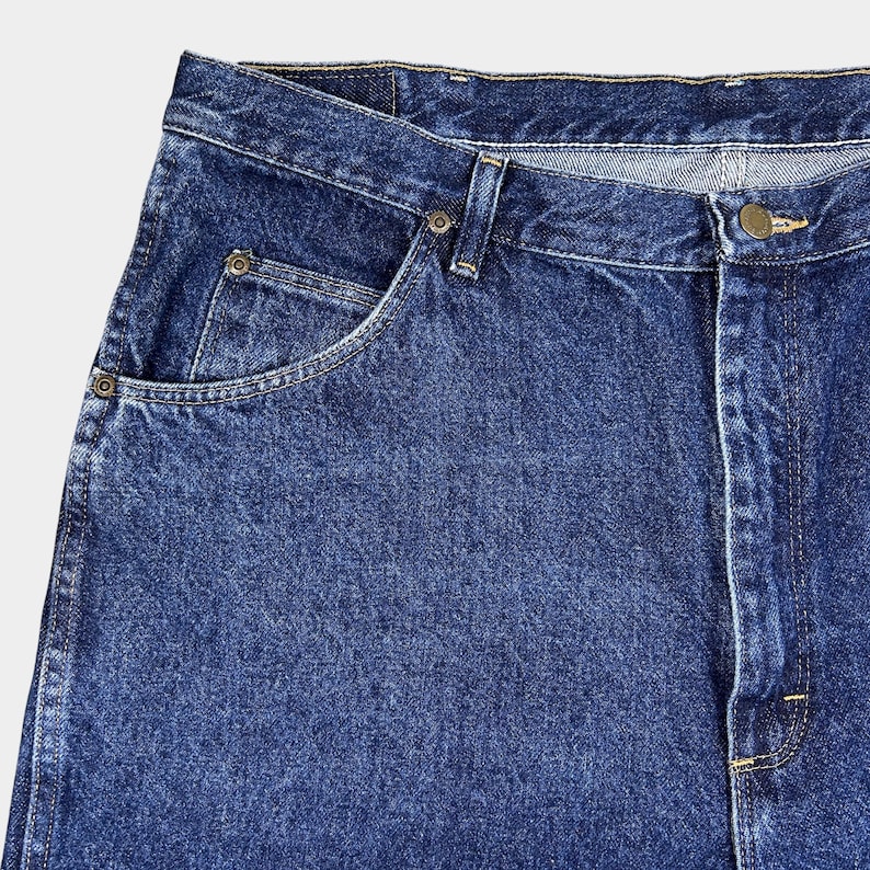 Pu&ograve; includere: Un paio di jeans blu denim con un classico design a cinque tasche. I jeans hanno un lavaggio chiaro e un aspetto sbiadito.