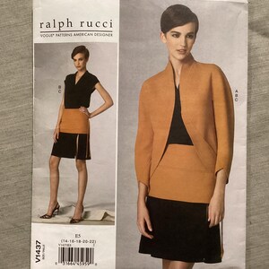 Pode incluir: Um padrão de costura Vogue Patterns de Ralph Rucci. O padrão apresenta um conjunto de duas peças com uma saia preta e um casaco bege. O número do padrão é V1437, e a gama de tamanhos é 14-22.