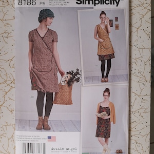 May include: Simplicity pattern 8186 features wrap dresses. The pattern includes sizes 12-20. The cover shows three different dress styles with floral prints. The pattern is designed and printed in the USA.